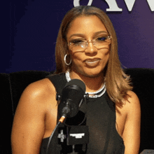 a woman wearing glasses is sitting in front of a microphone that says " hollywood gossip " on it