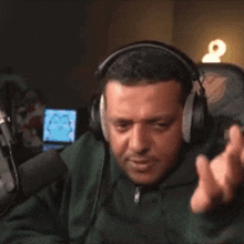 a man wearing headphones is sitting in front of a microphone and holding his head .