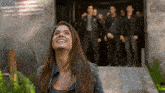 a woman is smiling in front of a group of men standing in front of a building with the word cab on it .