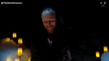 a man in a dark room with candles in the background has the hashtag thekamdreesen