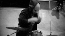 a man in a hooded sweatshirt is playing drums