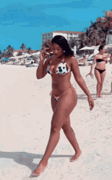 a woman in a cow print bikini is walking on the beach