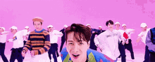 a group of men are dancing in front of a purple background .