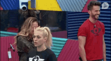 a man in a red shirt with a mini on it stands next to two women