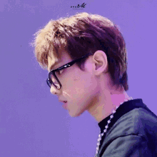 a close up of a person wearing glasses and a necklace