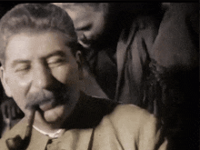 a man with a mustache is smoking a pipe in a black and white photo