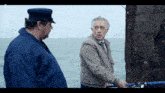 two men standing next to each other with a french logo on the bottom left corner