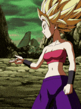 a woman in a pink top and purple pants stands in a rocky area