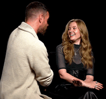 a man and a woman are looking at each other and the woman is smiling