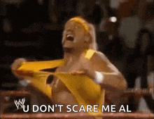 a wrestler in a yellow outfit is screaming and saying " u don t scare me al "