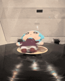 a stuffed animal with blue hair is on a record