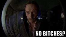 a man looking through a peephole with the words " no bitches " on the bottom