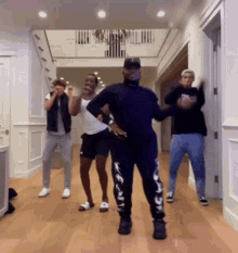 a group of people are dancing in a hallway with a man wearing a black shirt that says nike on the side
