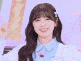 a girl with a bow in her hair is smiling and wearing a blue shirt and sweater .