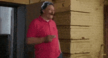 a man with a mustache is smoking a cigarette and pointing at the camera .