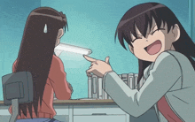 a girl is pointing at another girl who is laughing