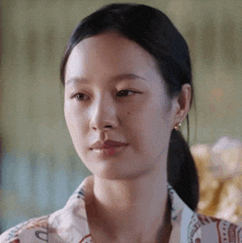 a close up of a woman 's face with a ponytail looking at the camera .
