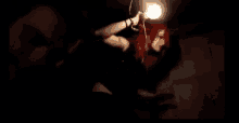 a woman with red hair is holding a light bulb in her hand in the dark