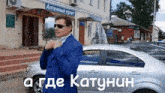 a man in a blue suit adjusts his tie in front of a silver car