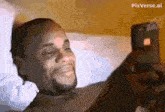 a man laying on a bed looking at a cell phone with pixverse.ai written on the bottom