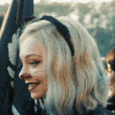 a blonde woman wearing a headband with a cat face painted on it