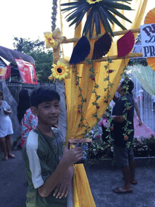 a boy stands in front of a yellow curtain with a sign that says pr on it