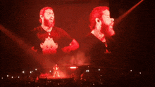 a man with a beard is standing on a stage in front of a crowd in a dark room