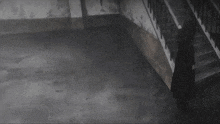 a person in a black coat is standing in a dark room next to stairs