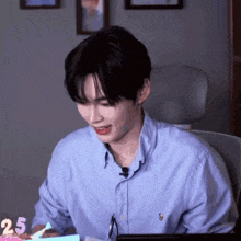 a man in a blue shirt is sitting at a table with a candle that says 25