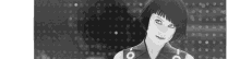 a black and white photo of a woman standing in front of a polka dot background .