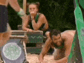 a man and a woman are playing in the sand while a woman looks on .