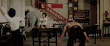 a group of people are standing in a room with a red sign on the wall that says ' chinese ' on it