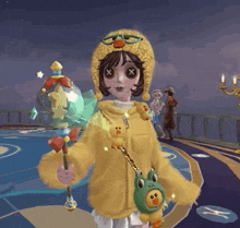 a girl wearing a yellow sweater and a duck hat is holding a stick and a frog purse .