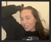 a woman in a black sweater is smiling while holding a glass of water
