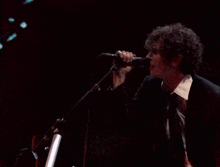 a man in a suit and tie is singing into a microphone on a stage