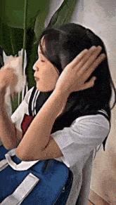 a girl in a sailor suit is holding a blue bag and brushing her hair .