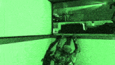 a soldier is climbing up a wall in a video game with a green light behind him .