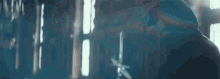 a man is standing in front of a window in a dark room with a sword in his hand .