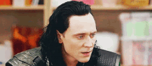 a close up of a man 's face with long black hair .