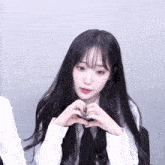 a girl with long black hair making a heart with her hands