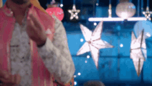 a man in a pink jacket is standing in front of a display of christmas decorations