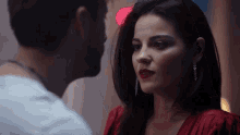 a man and a woman are looking at each other and the woman is wearing a red dress
