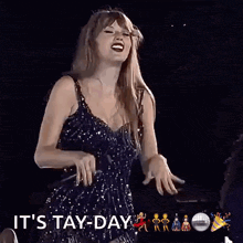 a woman in a black dress is singing into a microphone and the words it 's tay-day are next to her