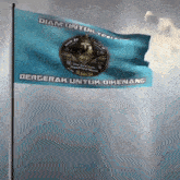 a blue flag that says bergerak untuk dikenang is flying in the wind