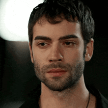 a close up of a man 's face with a beard and black shirt