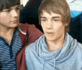 two young men are standing next to each other and looking at the camera .
