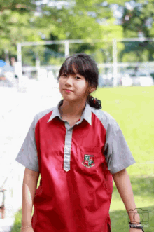 a girl wearing a red shirt with a badge that says ' tcs ' on it