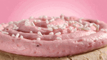 a cookie with pink frosting and white sprinkles on it