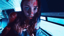 a woman with blood on her face is standing in a dark room .