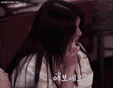 a woman with long black hair is talking on a cell phone in korean .